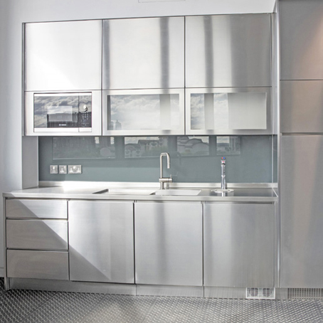 chrome effect kitchenette with sink, drawers, grey cupboards with transparent glass panels, reflecting the buildings outside