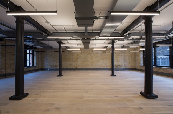symmetrical workspace with black pillars wooden floors and brick walls in Southwark