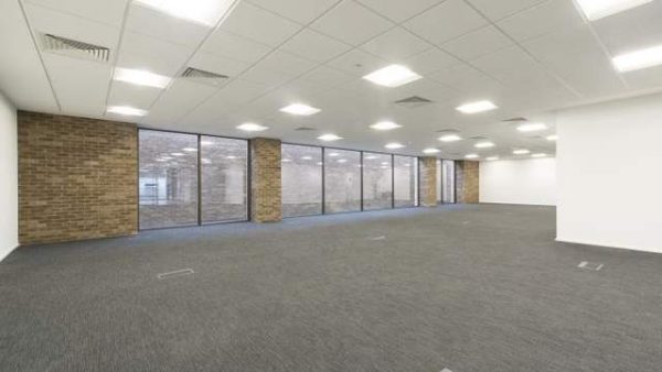 office space with white walls, brick structuring, floor to ceiling windows and a grey carpet