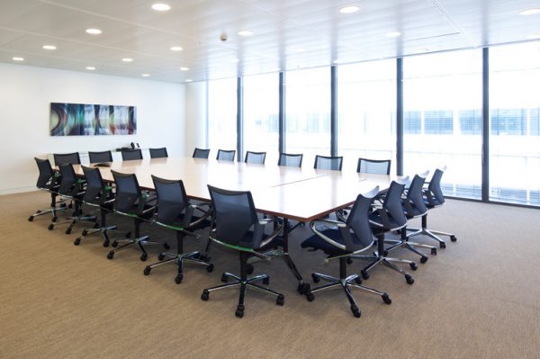 tidy meeting room with office chairs neatly and perfectly arranged around table and abstract picture mounted on the wall