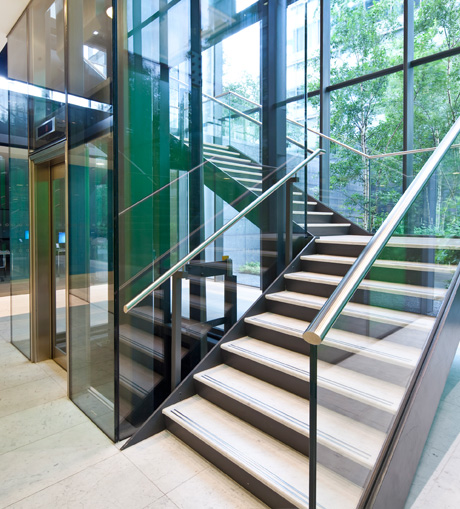 two short adjoining flights of stairs next to a lift going up, glass sides and polished rails