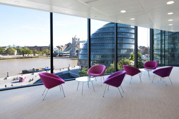 fuschia pink chairs round little glass coffee tables with a spectacular view of the neighbouring building, river Thames and the famous Tower Bridge