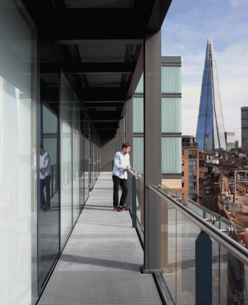 an outside balcony offers a view of the busy street and railway line below, with the Shard dominating the views further