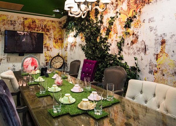 Mad Hatter style meeting room with wall creeper, vibrant coloured walls and furniture with tea cups set on green turf table piece