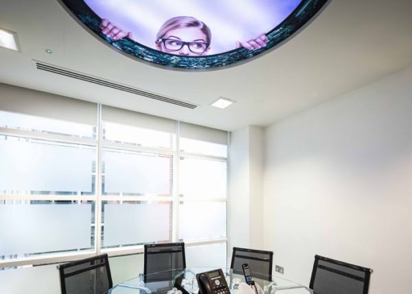 Alice in Wonderland inspired ceiling with woman's face peering in and meeting room below