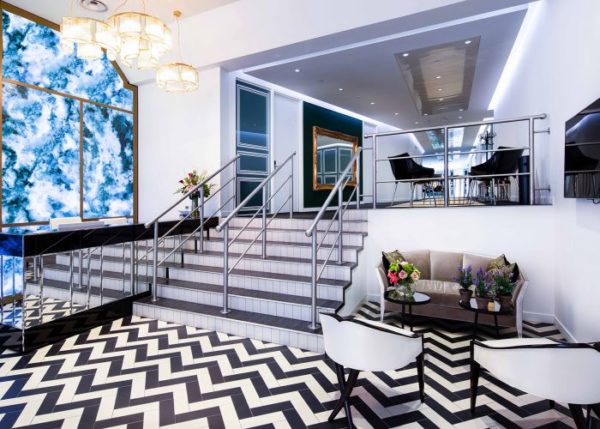 break out area with black and white zigzag tiled floor, flowers on tables and blue and white tie dye design on one wall and stairs leading up to higher level tables and chairs